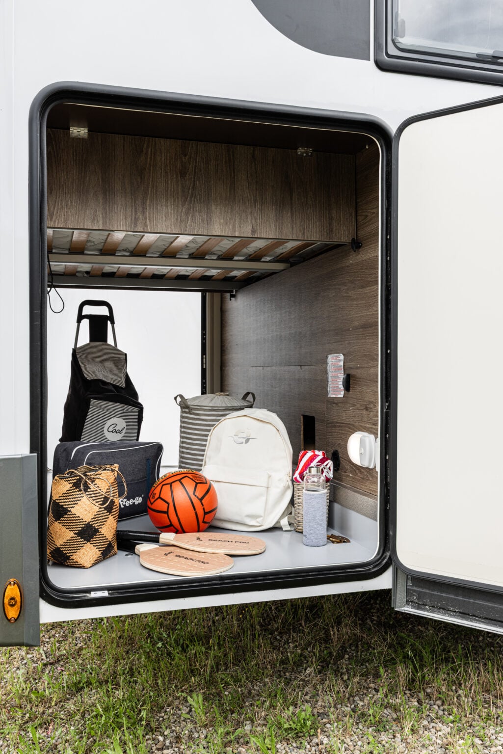 gavone laterale aperto di un camper CI, con rivestimento interno in legno e letto superiore a doghe visibile